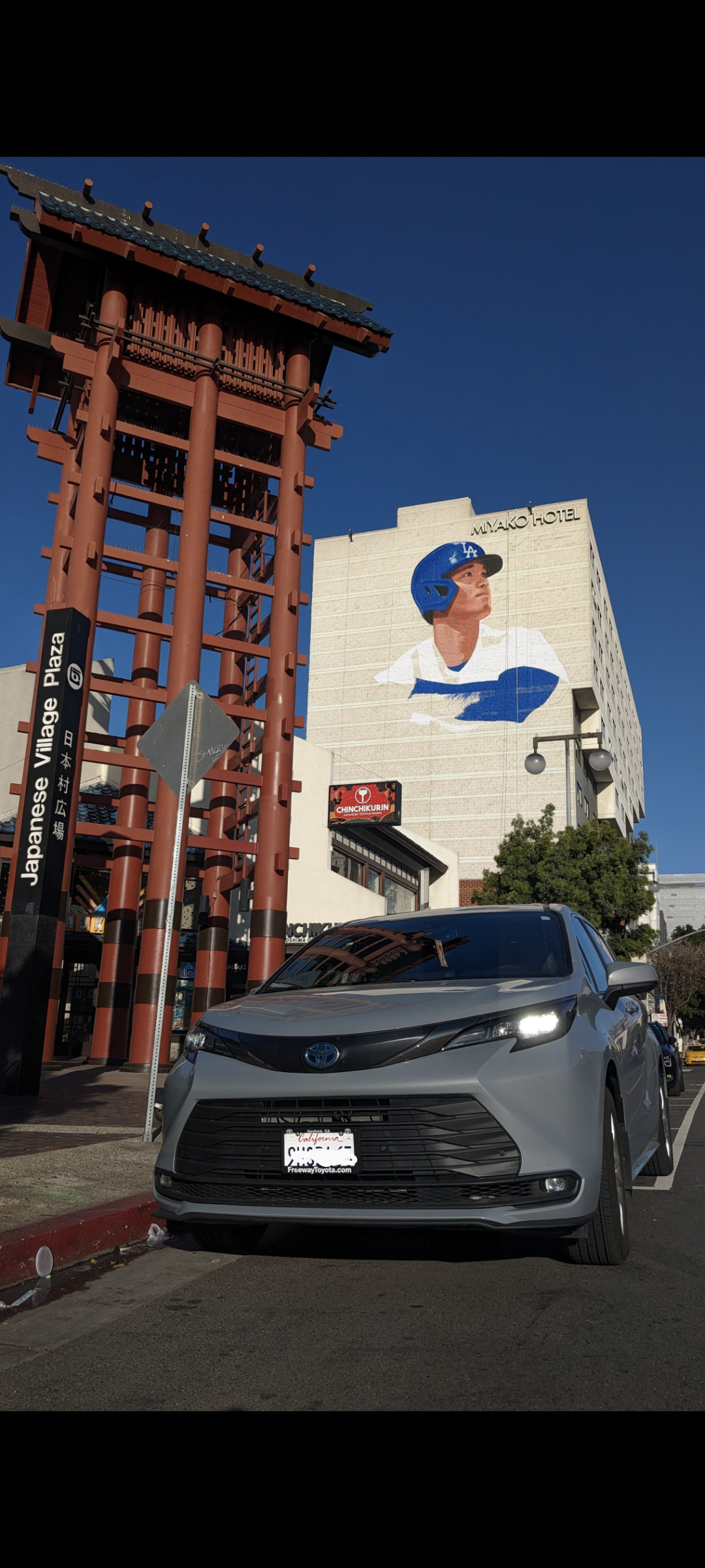 An impressive mural adorns the exterior of the Miyako Hotel Los Angeles, depicting Shohei Ohtani, the dynamic baseball player, in action. Vibrant colors capture the essence of his athleticism and determination, adding a touch of excitement to the urban landscape."